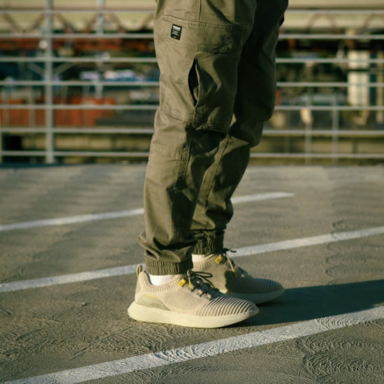 Man walking on rooftop of parking lot wearing green cargo pants and SNNCE Sneakers